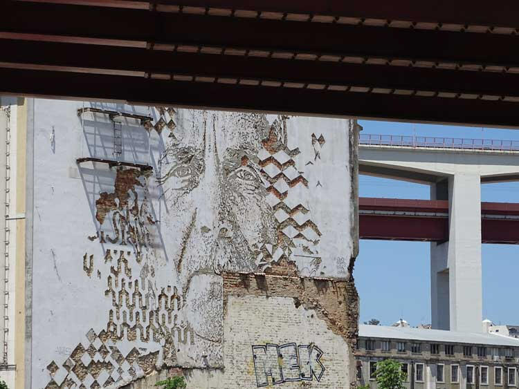 Street art, Lisbon - artist Vhils carves into building facades to reveal layered histories embedded within the city’s fabric.